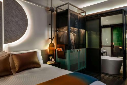 a bedroom with a tub and a bed and a bath room at QT Newcastle in Newcastle