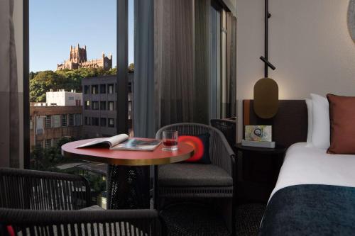 a hotel room with a bed and a table and a window at QT Newcastle in Newcastle