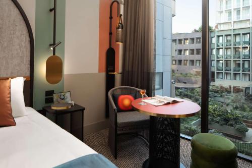 a hotel room with a bed and a table and a window at QT Newcastle in Newcastle