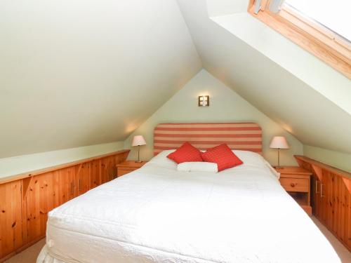 a bedroom with a white bed with two red pillows at The Coach House in Duns