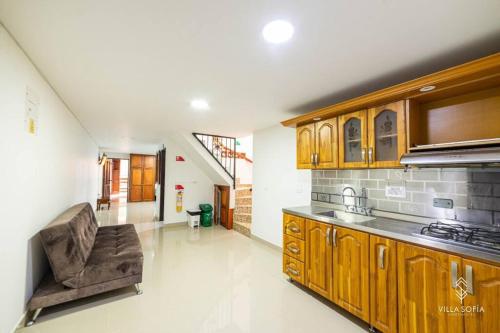 a kitchen with wooden cabinets and a couch in a room at Aparta Hotel Villa Sofia in Jericó