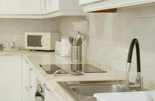 una cucina bianca con un lavello e un forno a microonde di Casa da Lota 1º, by Casas do Verão a Manta Rota