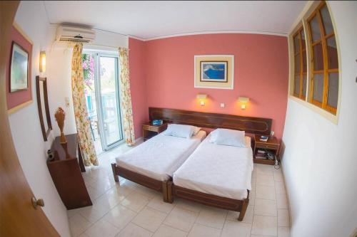 羅德島卡利地亞的住宿－Aphrodite Apartments，一间卧室设有两张床和红色的墙壁