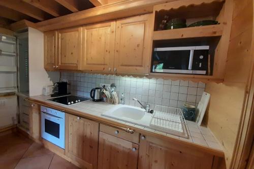 a kitchen with wooden cabinets and a sink at Quiet apartment near the slopes in La Clusaz