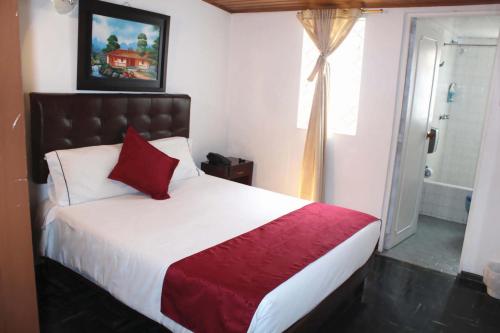 a bedroom with a large bed with a red blanket and a window at Casa Hotel Victoria in Bogotá