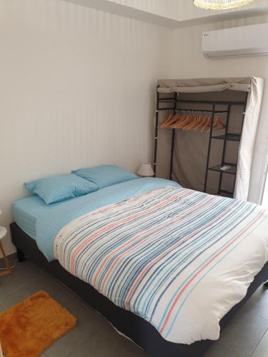- une petite chambre avec un lit et une couverture rayée dans l'établissement Une heureuse coïncidence, à Montpellier