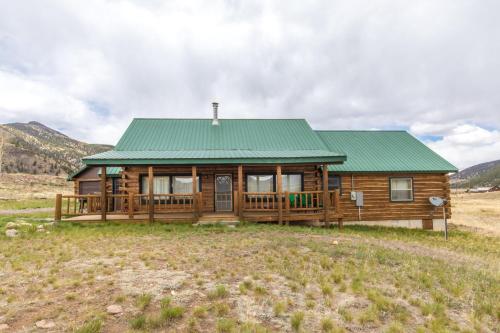 a wooden cabin with a green roof in a field at Charming Starlight Cabin in Creede