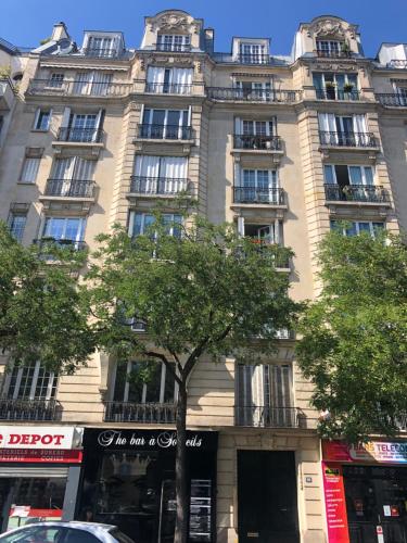 un grand bâtiment avec un arbre devant lui dans l'établissement Cosy studio Paris 16 métro Exelmans, à Paris