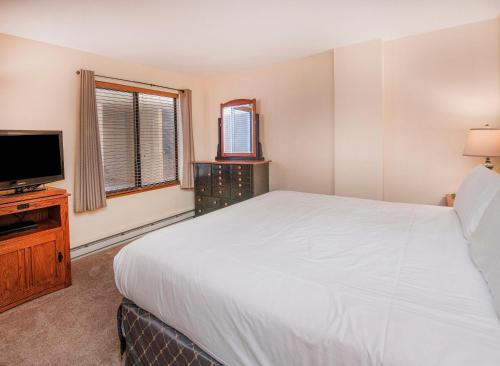 a bedroom with a large white bed and a television at The Seasons Unit 205 in Avon