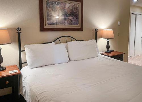 a bedroom with a bed with white sheets and two lamps at The Seasons Unit 205 in Avon
