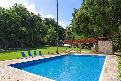 a swimming pool with blue chairs and a pavilion at Vila Siriúba Hotel in Ilhabela