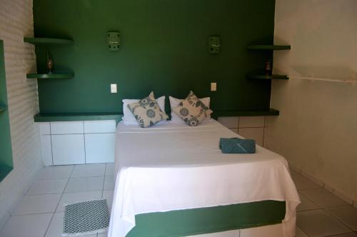 a bed in a room with a green wall at Pousada La Luna in Paracuru