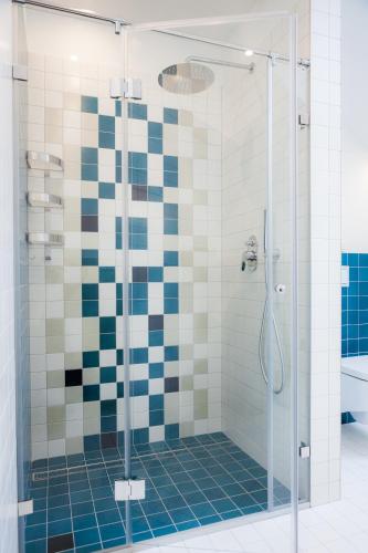 a bathroom with a shower with blue and white tiles at Vila Nikolas in Druskininkai
