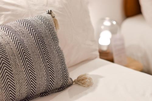 a black and white pillow with a tassel on a bed at Mestizo Antigua in Antigua Guatemala