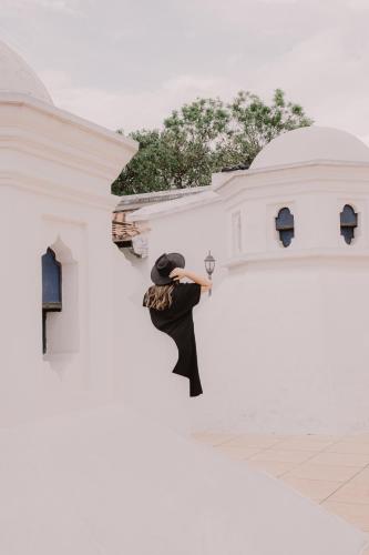 a woman standing on the side of a white building at Mestizo Antigua in Antigua Guatemala