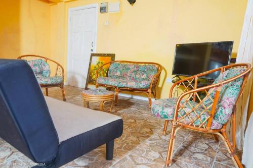a living room with chairs and a flat screen tv at Belle View-Tulip in Laborie