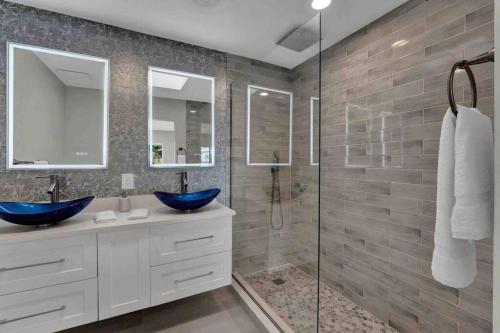 uma casa de banho com 2 lavatórios azuis e uma cabina de duche em vidro. em Luxurious 5 bedroom lake house 3min from Universal em Orlando