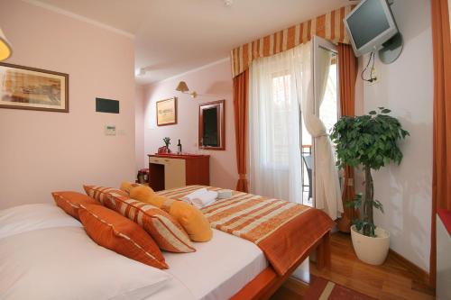 una camera da letto con un letto con cuscini arancioni sopra di Hotel Trogir a Trogir