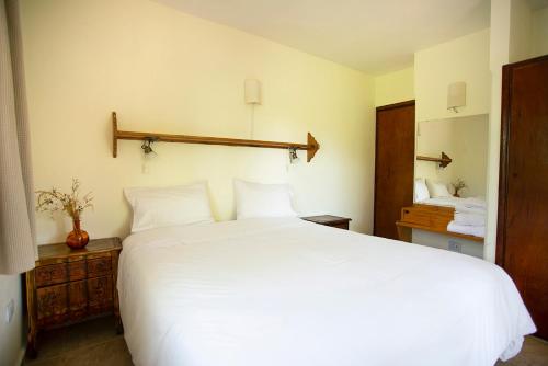 a bedroom with a large white bed with white pillows at Hotel Las Cascadas in La Cumbrecita