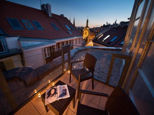 Un balcón con una silla y un libro sobre una mesa en EA Embassy Prague Hotel, en Praga