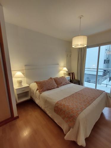 um quarto com uma cama grande e uma janela grande em Hermoso Departamento 2 amb con cochera en Plaza Mitre em Mar del Plata
