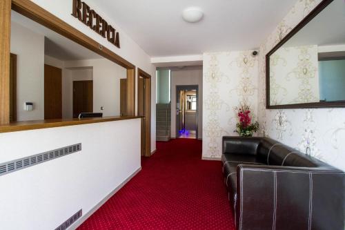 a waiting room with a leather couch and a mirror at La Pension in Trnava