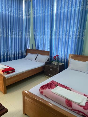 two beds in a room with blue curtains at MINH THU MOTEL in An Bình (1)