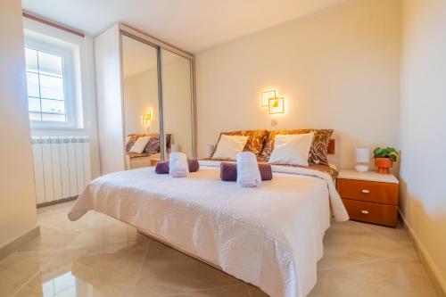 a bedroom with a large white bed and a window at Apartments Laganini in Novi Vinodolski