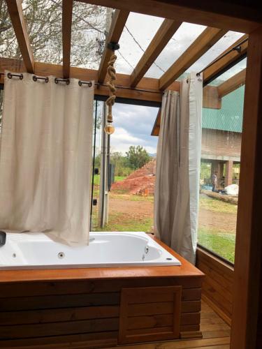 a bath tub in a room with a window at Chalé Recanto Verde dos Canyons in Praia Grande