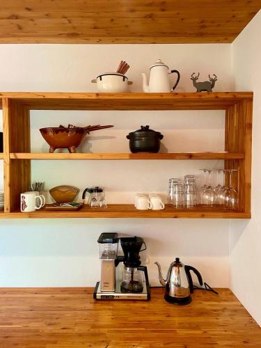 a kitchen with wooden shelves with dishes and a coffee maker at Fuku Chalet in Hakuba