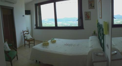 1 dormitorio con cama blanca y ventana en Bed And Breakfast San Martino, en Castignano