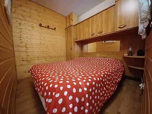 a bedroom with a bed with a red and white comforter at Charmant 2 pièces avec balcon et parking au Col du Corbier - FR-1-573-107 in Le Biot