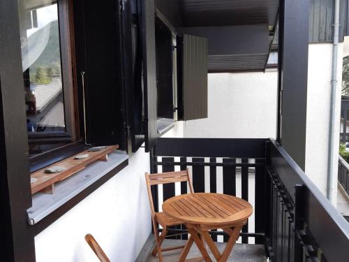 une chaise en bois assise sur un balcon à côté d'une fenêtre dans l'établissement Charmant T2 calme avec balcon et parking à Chamonix - FR-1-517-64, à Chamonix-Mont-Blanc