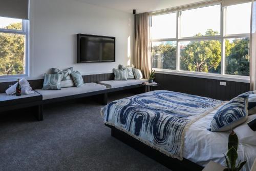 - une chambre avec un lit, une télévision et des fenêtres dans l'établissement Beach Road Hotel, à Sydney