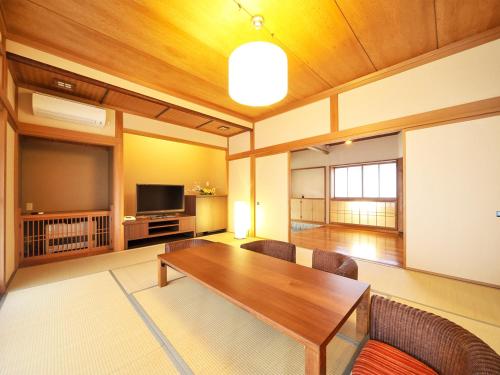 a living room with a wooden table and a television at Takanosukan in Sekikawa