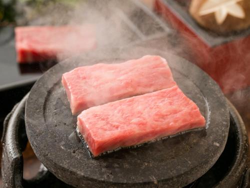 two pieces of meat cooking on a grill at Takanosukan in Sekikawa