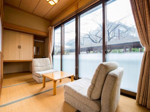 a living room with two chairs and a table and large windows at Takanosukan in Sekikawa