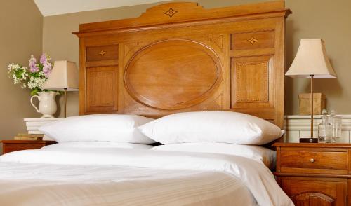 a bed with a large wooden headboard and white pillows at Courtyard Cottages in Tralee