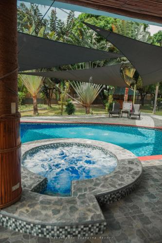 a swimming pool with a table and an umbrella at Shenanigans Glamping Resort in Zamboanguita