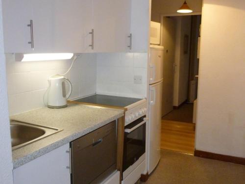 une petite cuisine avec des armoires blanches et un évier dans l'établissement Appartement 3P rénové, balcon, proche pistes et commerces - FR-1-425-126, à Flaine