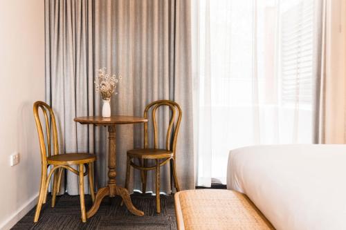 a bedroom with a table and two chairs next to a bed at The Ned Ryan Motel in Boorowa