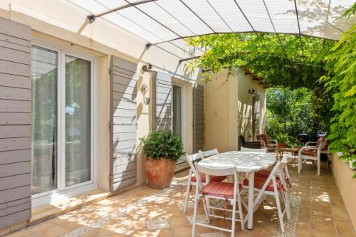 une terrasse avec une table blanche et des chaises. dans l'établissement Superbe maison avec terrasse et piscine - Villeneuve-lès-Avignon - Welkeys, à Villeneuve-lès-Avignon