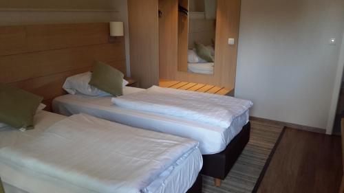 two beds in a small room with a mirror at Der Heidkrug in Verden