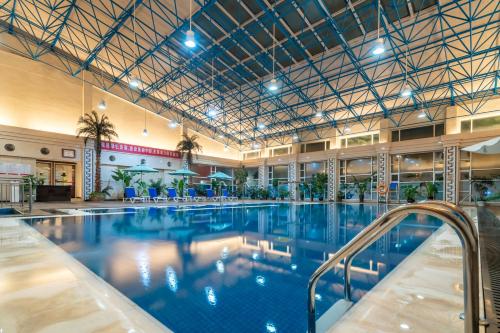 ein großer Pool mit blauem Wasser in einem Gebäude in der Unterkunft Ramada Plaza Taian in Tai'an