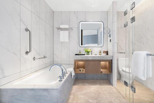 a bathroom with a tub and a sink and a toilet at Somerset Gaoxin Chengdu in Chengdu