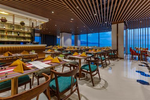 a restaurant with wooden tables and chairs and windows at Le Sands Oceanfront Danang Hotel in Da Nang