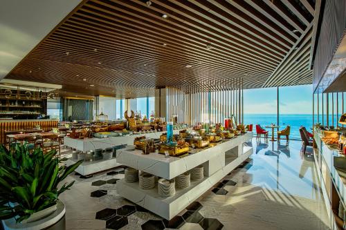 a restaurant with tables and chairs and the ocean at Le Sands Oceanfront Danang Hotel in Da Nang
