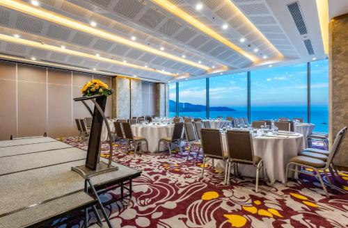 a banquet room with tables and chairs and large windows at Le Sands Oceanfront Danang Hotel in Da Nang