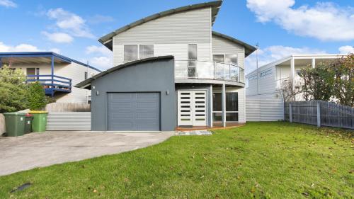 a house with a garage and a grass yard at Shore Thing Upstairs - Coastal Family Retreat in Lake Tyers