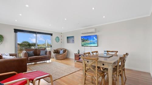 a living room with a table and chairs at Shore Thing Upstairs - Coastal Family Retreat in Lake Tyers